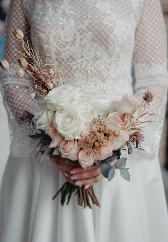 about-img Close-up of a bride holding a delicate bouquet with a lace wedding dress, showcasing elegance and romance.