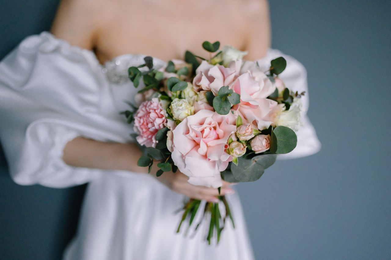 Close-up of a bride holding a lush bouquet of pink and white flowers, perfect for wedding inspiration.